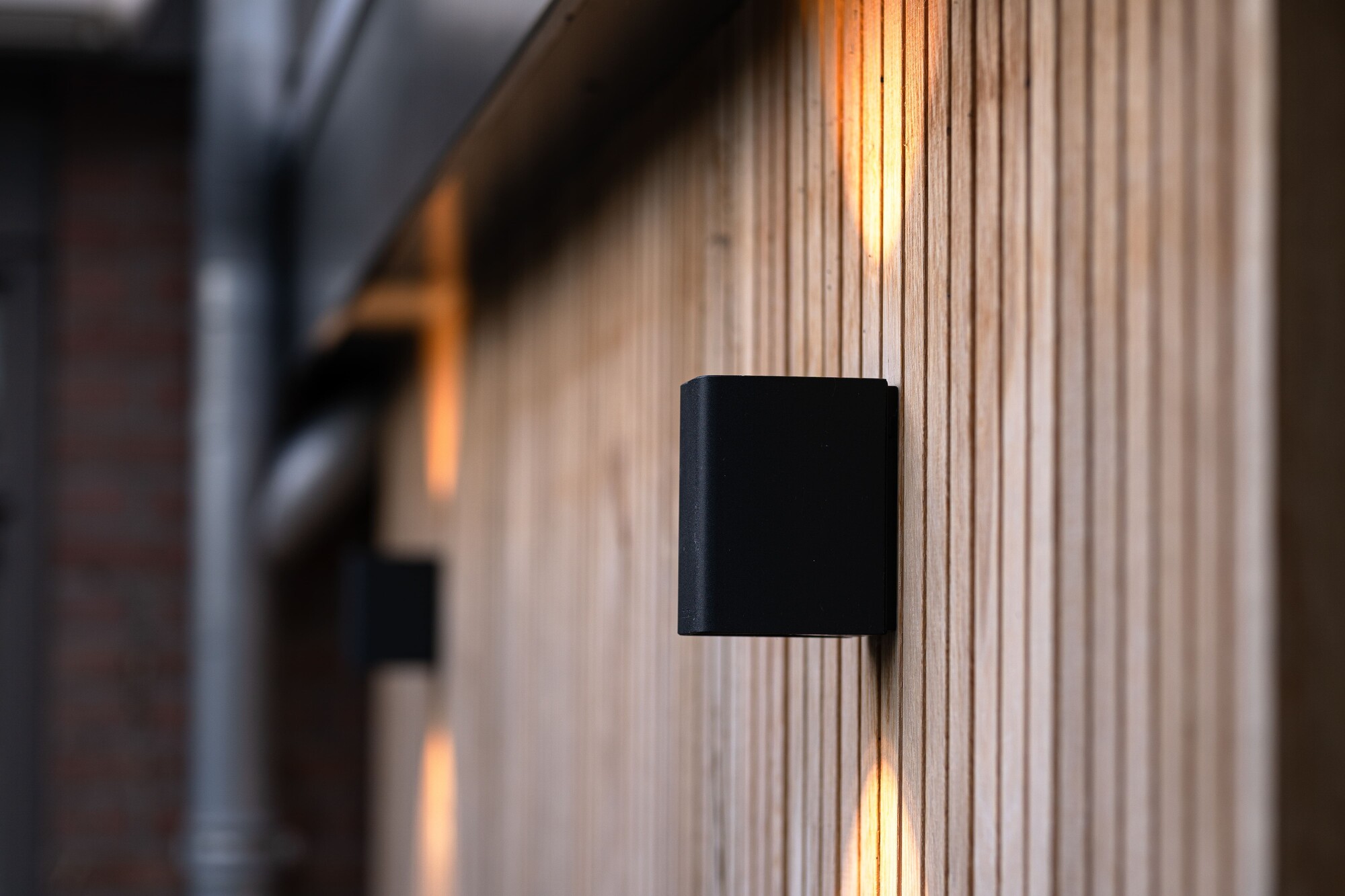Eine Up-and-Down-Wandleuchte f&uuml;r au&szlig;en von in-lite an einer holzverkleideten Au&szlig;enwand